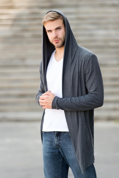 Male fashion influencer. Fashionable young model man. Carefree guy street style outfit with hood. Handsome man with hood standing urban background. Fashion trend. Comfortable clothes for daily wear.