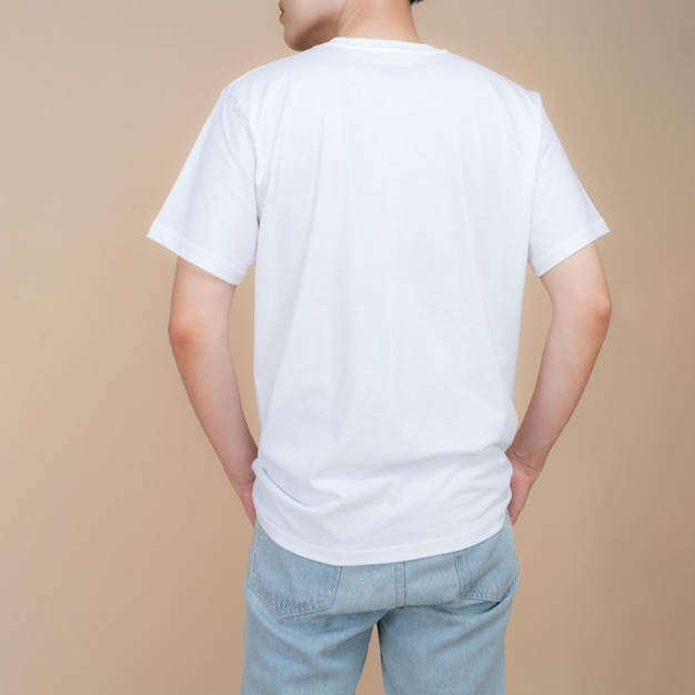 Male fashion model in white tshirt and jeans standing in studio on beige background