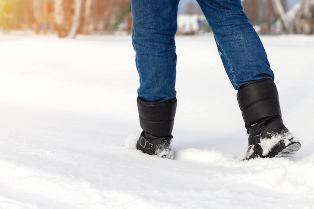 Male feet in black boots, winter walking in snow