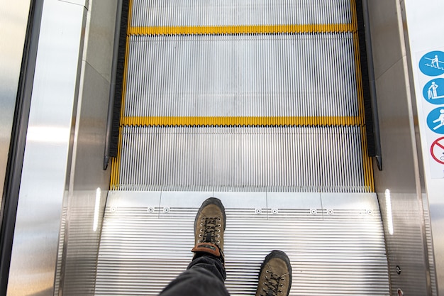 Male feet on the escalator, top view.