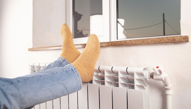 Male feet with socks on the radiator. Heating season.