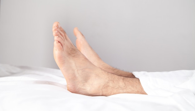 Male feets on the bed in morning.