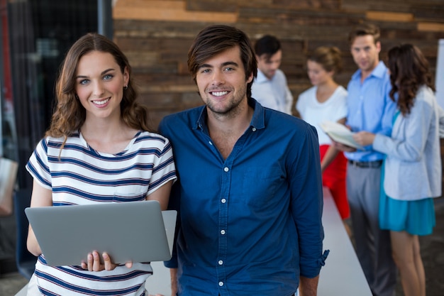 Male and female business executives holding laptop