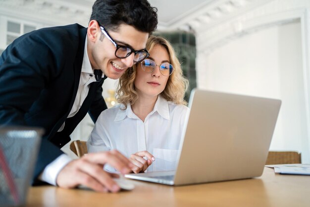 Male and female colleagues work in the office and use laptops in the workplace