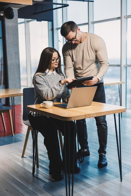 Male and female colleagues work together in a modern office on a project Workers in the office behind the satellite work with a laptop Subordinate and manager