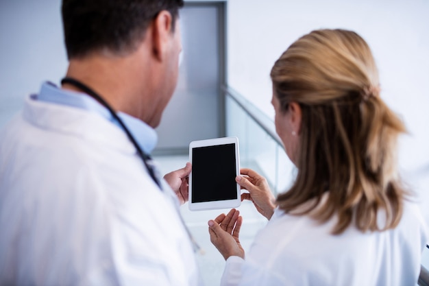 Male and female doctor discussing over digital tablet