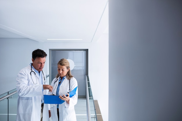 male and female doctor discussing over a report in the passageway