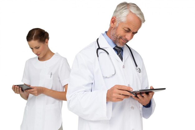 Male and female doctors using digital tablets over white background