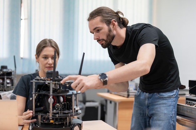 Ingegneri maschi e femmine testano e controllano il modello di robot ai nella sala del laboratorio di robotica dell'accademia