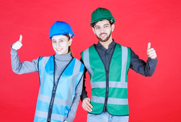 Male and female engineers with helmets feeling powerful and positive.