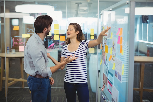 Male and female executives discussing over whiteboard