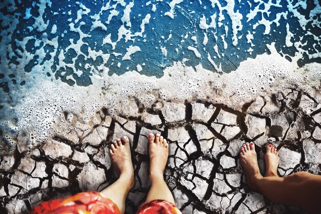 Male and female feet are standing on the dry land on coast