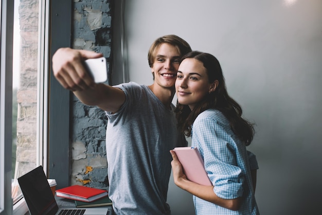 male and female friends clicking selfie pictures for sharing to social networks using frontal camera