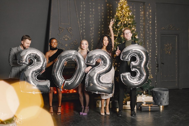 Photo male and female friends in standing with balloons 2023 for new year's celebration