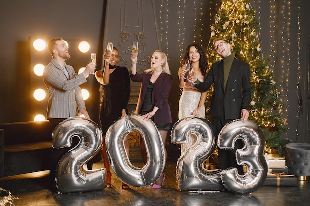 Male and female friends in standing with balloons 2023 for New Year's celebration