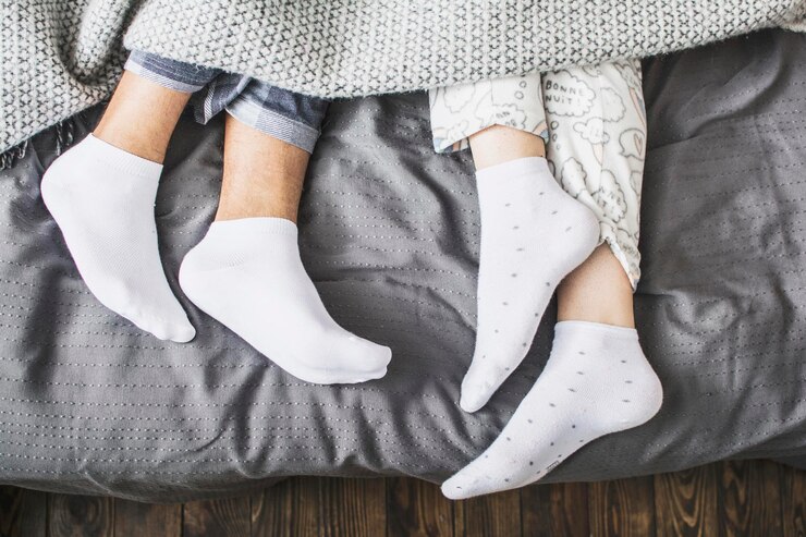 Male and female legs in socks under a blanket in a bed