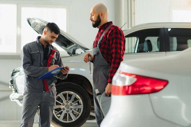 Male and female mechanics working on car