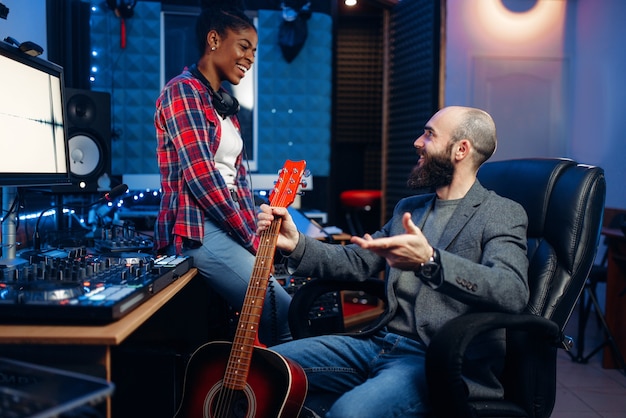 Male and female musicians in sound recording studio. Performers on record, professional music mixing