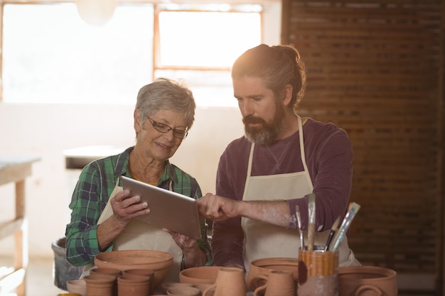 Male and female potter using digital tablet