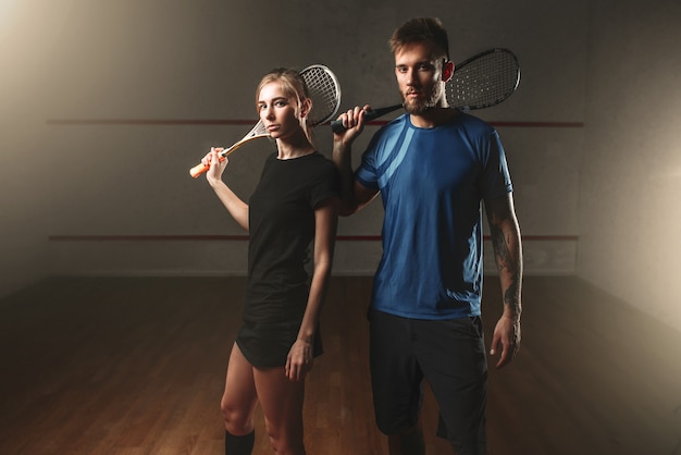 Male and female squash game players with rackets.