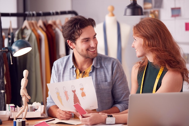 Male And Female Students Or Business Owners Working On Designs In Fashion Studio Together