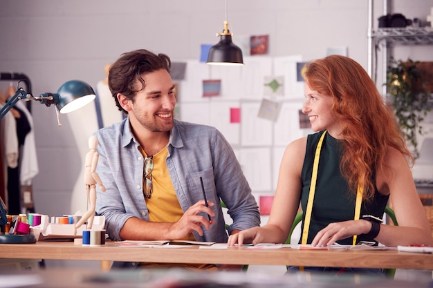 Male And Female Students Or Business Owners Working On Designs In Fashion Studio Together