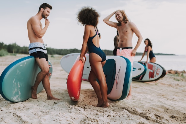 Surfisti maschii e femminili che parlano alla spiaggia.