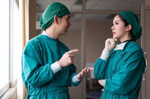 Photo male and female surgeon discussing about patient case at corridor in a hospital after finish surgery