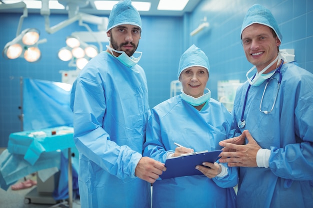 Мужской и женский хирург обсуждая над буфером обмена в театре операций