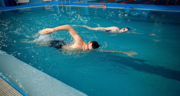 男性と女性のスイマーはプールで泳ぐ