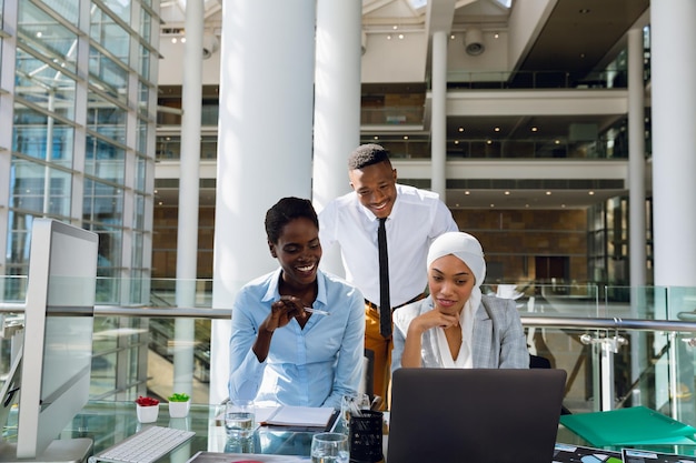 Male and females executives discussing over laptop at desk in office. Modern corporate start up new business concept with entrepreneur working hard