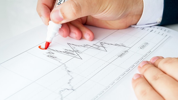 Male financial analyst writing financial graph or chart.