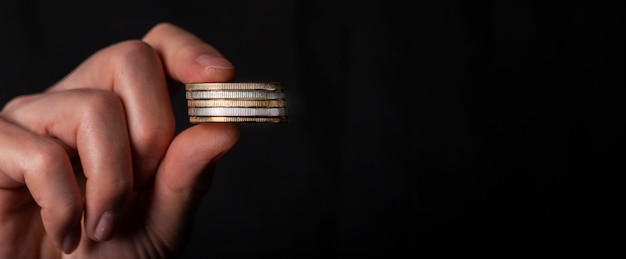 Male fingers holding stack of coins. Concept of money laundry, black false accounting. Banner with copy space for text.