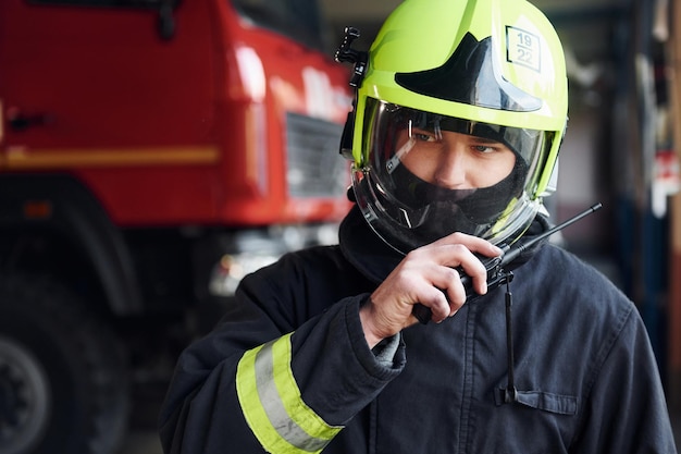 Male firefighter in protective uniform standing near truck