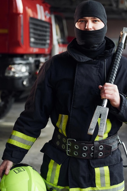 Male firefighter in protective uniform standing near truck