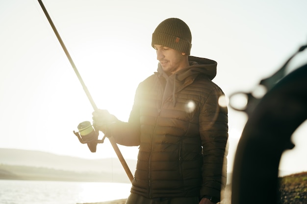 Male fisherman fishing at the lake at sunrise