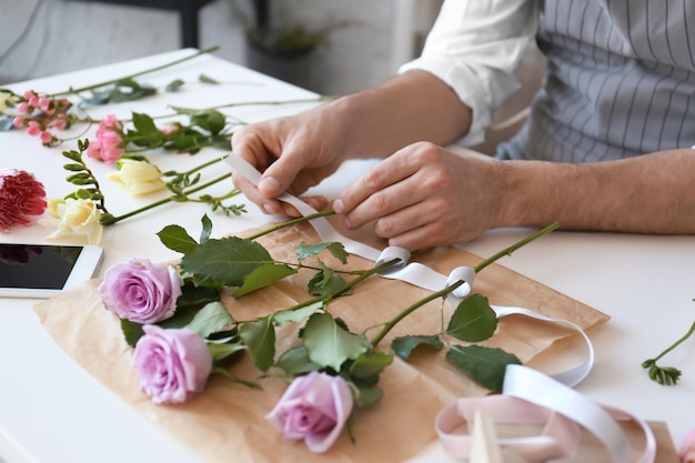テーブルのクローズ アップで美しい花束を作成する男性の花屋