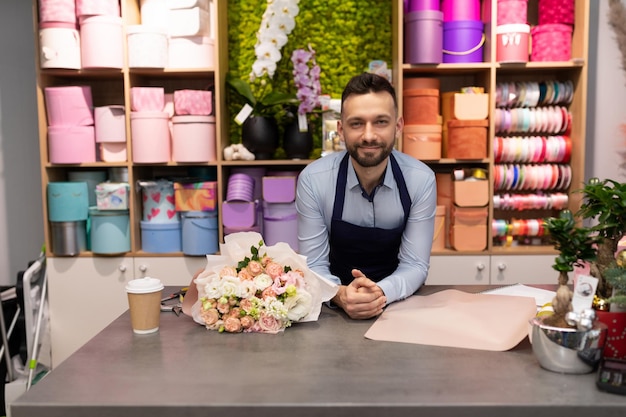 Male florist in a flower shop behind the counter next to a bouquet