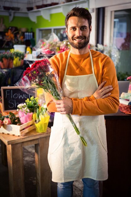 赤い花の束を保持している男性の花屋