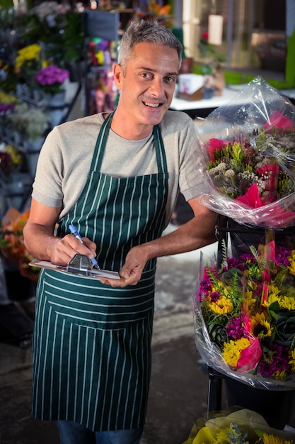 Male florist writing on clipboard