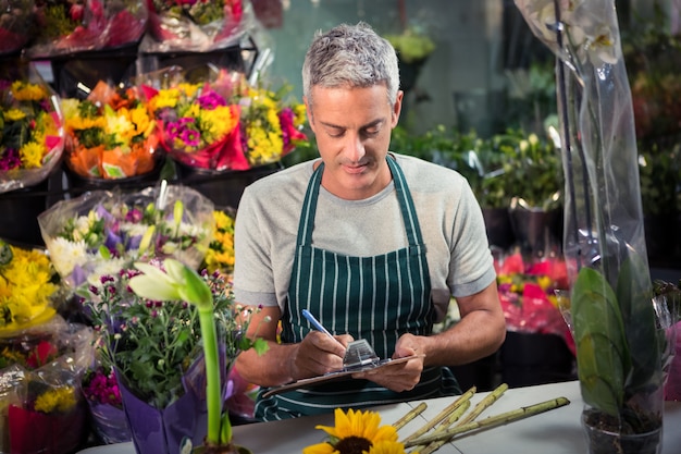 Male florist writing on clipboard