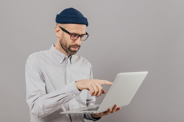 Male freelancer makes project work, points with index finger at screen of laptop computer