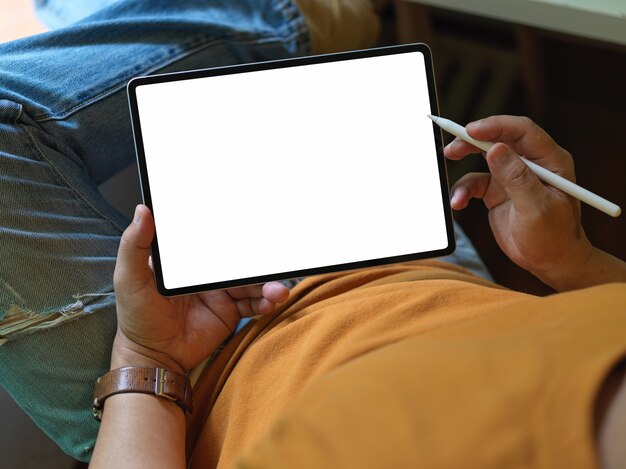 Male freelancer using blank screen tablet while lying relaxed on office chair