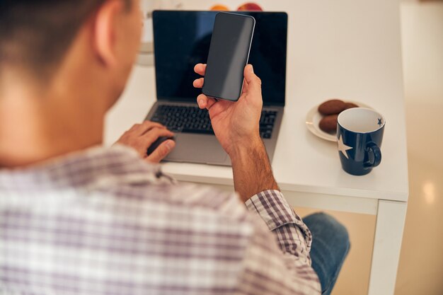 Male freelancer using his gadgets at breakfast