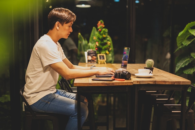 Male freelancer working on laptop at late night in coffee shop.