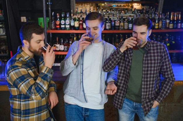 Male friends spending time together in bar and having fun Bearded men smiling looking at each other and communicating Men holding crystal glasses of whisky or scotch