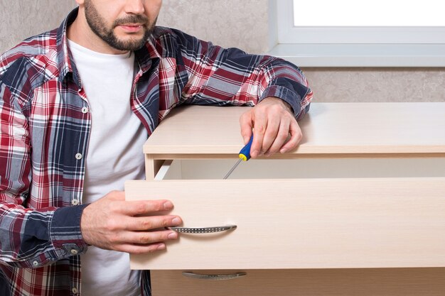 male furniture maker assembles furniture in an apartment