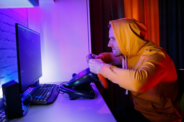 Male gamer playing racing games on the computer he uses the\
steering wheel emotional game