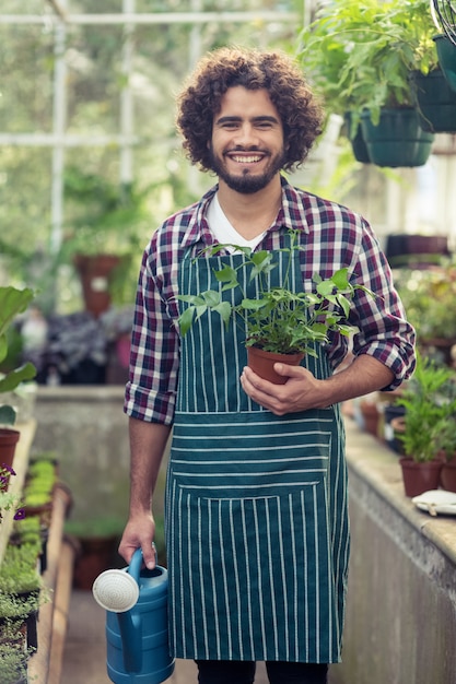 鉢植えの植物と水まき缶を保持している男性の庭師