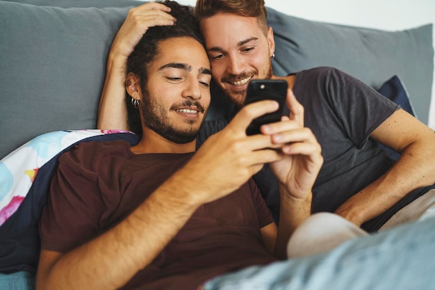 Male gay couple using smartphone in the bedroom  homosexual LGBT concept  focus on the left man